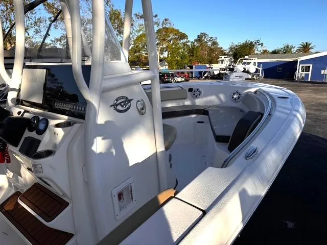 Slide: The Image of 2022 Tidewater 210 LXF boat interior with seating and console, parked outdoors. - 10