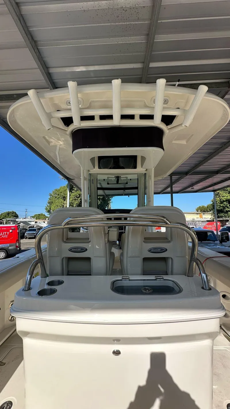 Slide: The Image of 2023 Boston Whaler 250 Outrage boat under a canopy, showcasing seating and helm. - 12