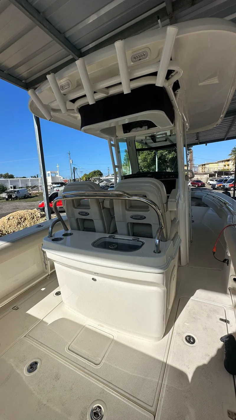 Slide: The Image of 2023 Boston Whaler 250 Outrage boat interior with seating and console under a canopy. - 15