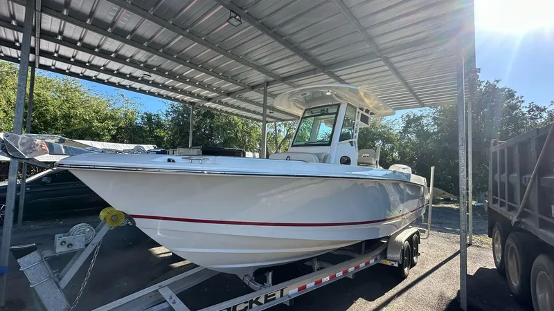 Slide: The Image of 2023 Boston Whaler 250 Outrage boat on trailer under a metal canopy. - 6