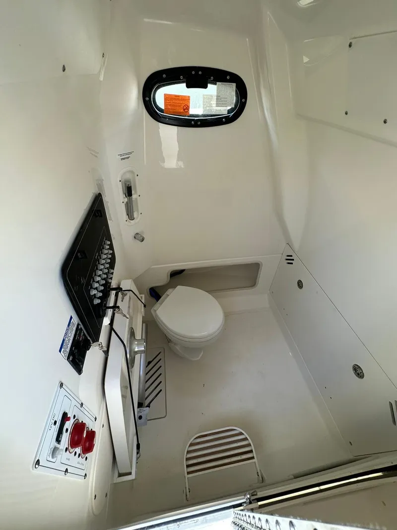 Slide: The Image of 2023 Boston Whaler 250 Outrage interior cabin with toilet and control panel. - 8