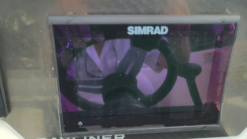 Slide: The Image of Simrad display on 2025 Bayliner D22 boat dashboard with steering wheel reflection. - 35