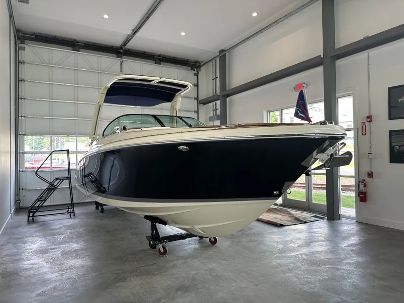 Slide: The Image of 2024 Chris-Craft Launch 28 GT boat in showroom, sleek design, navy hull, modern interior. - 19