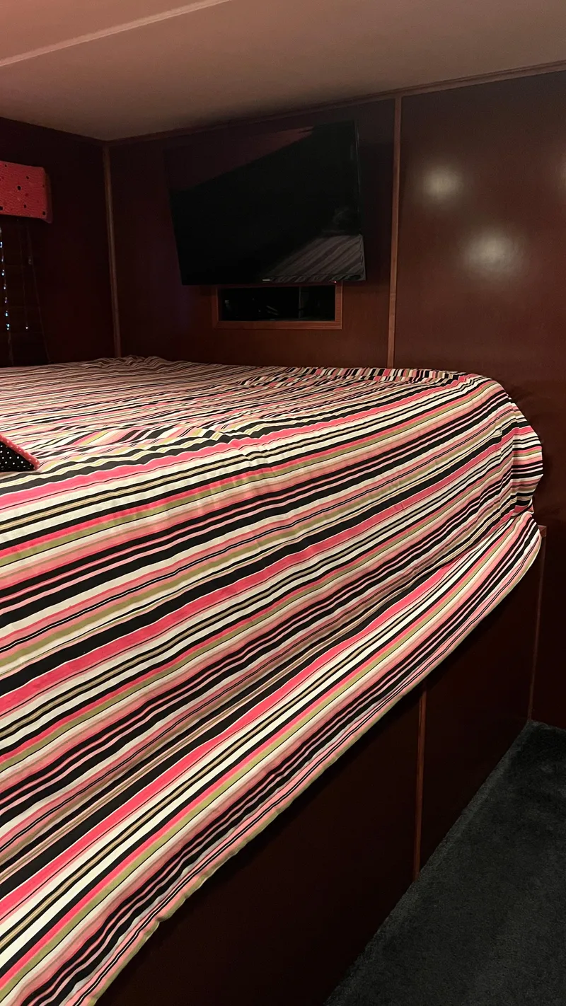 Slide: The Image of Cozy bedroom in 2008 Monticello River Yacht with striped bedding and wall-mounted TV. - 34