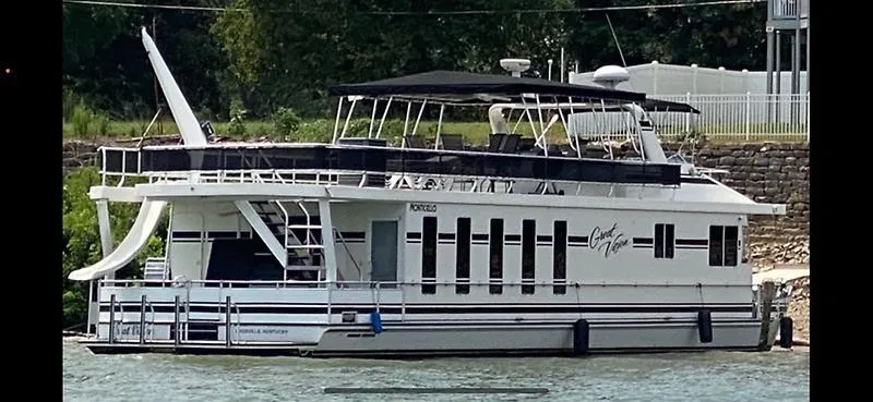 Slide: The Image of 2008 Monticello River Yacht docked by a stone wall, featuring a sleek design and upper deck. - 53