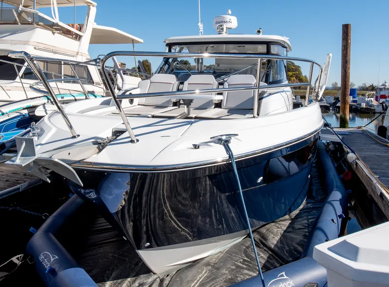 Slide: The Image of 2021 Jeanneau Leader 12.5 WA boat docked at marina, sleek design, white and blue exterior. - 11