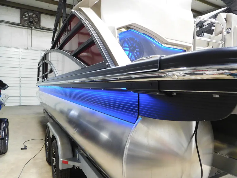 Slide: The Image of 2025 Bennington 25 QFB pontoon boat with blue LED lighting in a showroom. - 17