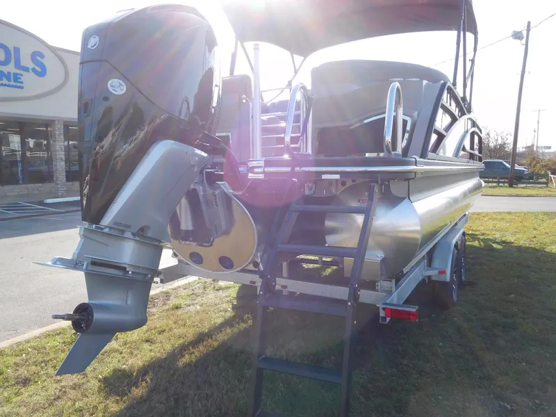 Slide: The Image of 2025 Bennington 25 QFB pontoon boat with powerful outboard motor, parked on grass. - 19