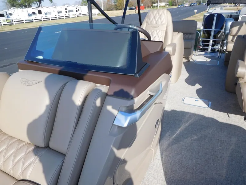 Slide: The Image of 2025 Bennington 25 QFB boat interior with beige seating and modern dashboard. - 7