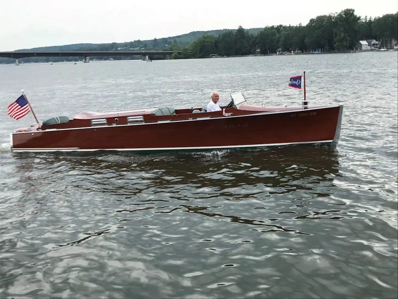 Slide: The Image of 1930 Chris-Craft Triple motorboat cruising on a lake with American flags. - 2