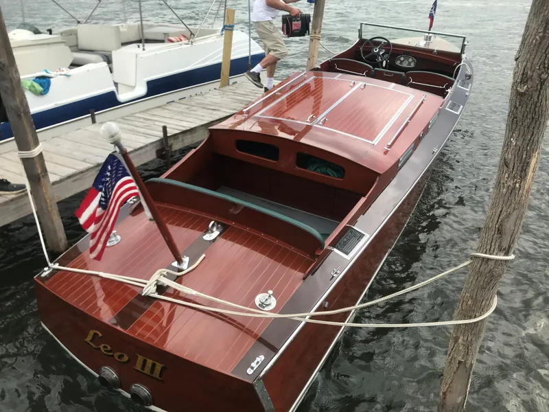 Slide: The Image of 1930 Chris-Craft Triple boat docked, rear view with American flag and Leo III name. - 8