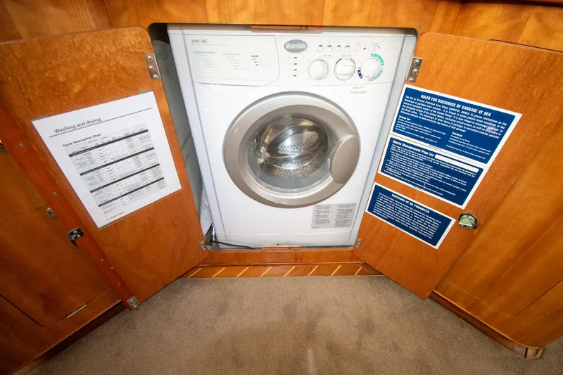 Slide: The Image of Washing machine inside Antares PDQ 44 yacht, 2004 model, with open wooden cabinet doors. - 30
