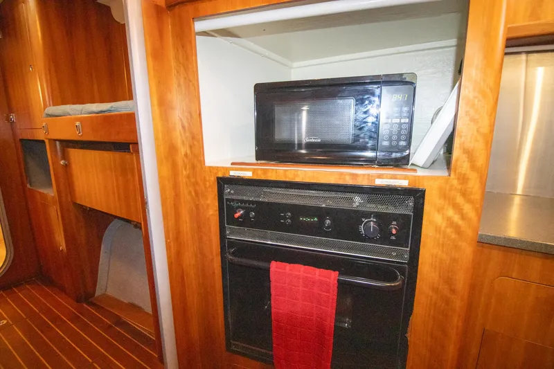Slide: The Image of Galley of 2004 Antares PDQ 44 with microwave and oven, featuring wood cabinetry. - 43