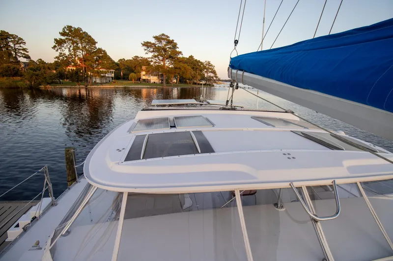 Slide: The Image of Sailing yacht Antares PDQ 44, 2004 model, docked by serene waterfront with trees. - 8