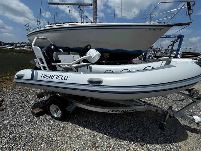 The Image of 2025 Highfield Classic 400 inflatable boat on trailer, parked near larger sailboat. - 0