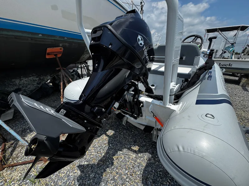 Slide: The Image of 2025 Highfield Classic 400 boat with Tohatsu outboard motor, docked on gravel. - 2