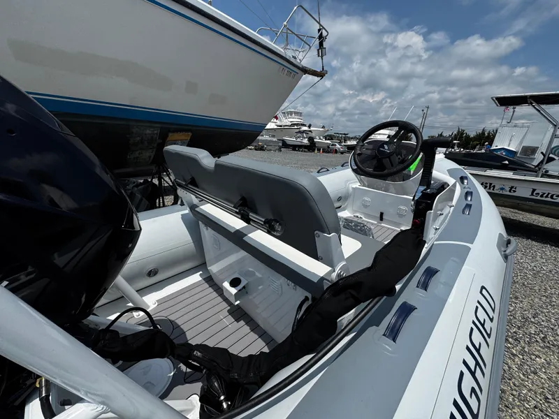 Slide: The Image of 2025 Highfield Classic 400 boat interior with steering wheel, docked under a cloudy sky. - 3
