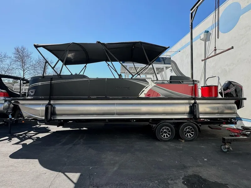 The Image of 2025 Tahoe Pontoon 2585 LTZ Entertainer boat on trailer, black canopy, outdoor setting. - 0