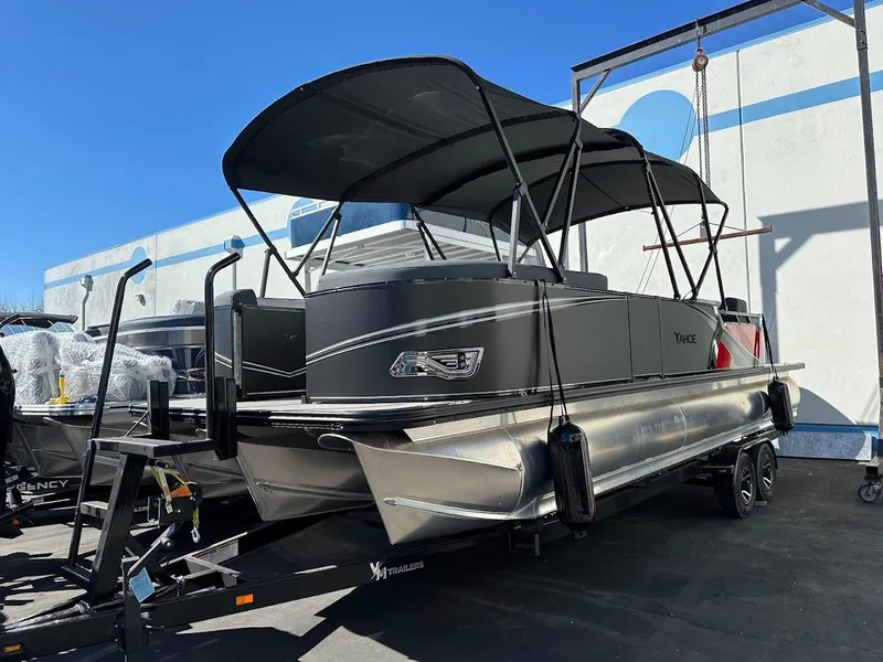 Slide: The Image of 2025 Tahoe Pontoon 2585 LTZ Entertainer boat on trailer, black canopy, outdoor display. - 2