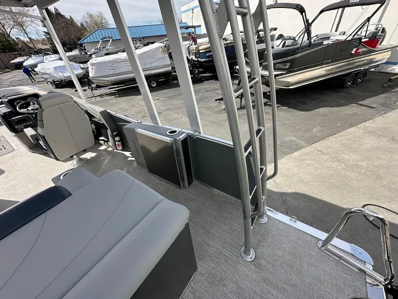 Slide: The Image of 2025 Tahoe Pontoon Cascade Cruise Funship interior with seating and ladder, parked outdoors. - 19