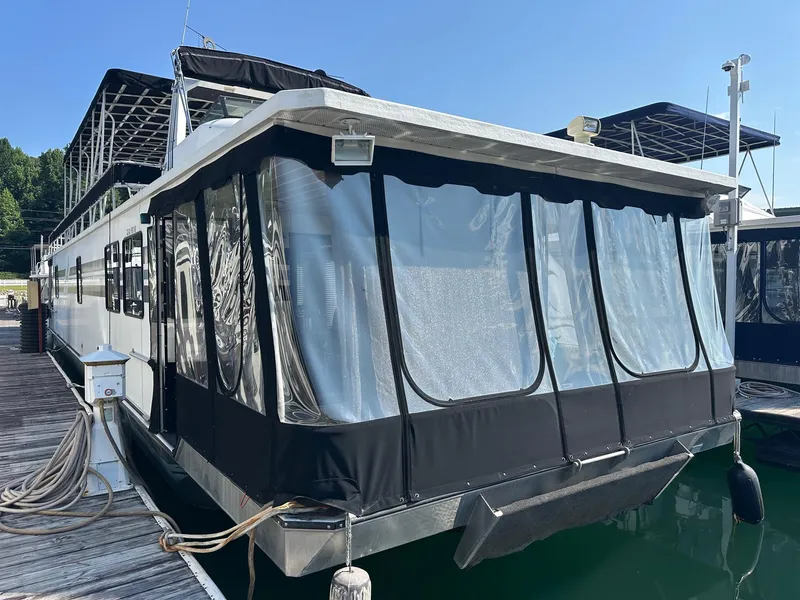 The Image of Houseboat docked at marina, Lakeview 15x70 model, 1995, with covered deck and clear windows. - 0