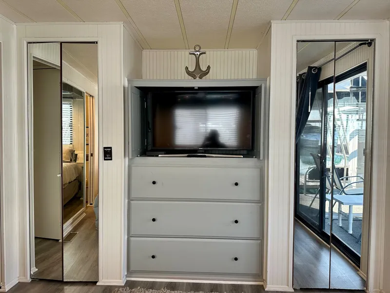 Slide: The Image of Interior of a 1995 Lakeview 15x70 houseboat with TV, drawers, and mirrored doors. - 10