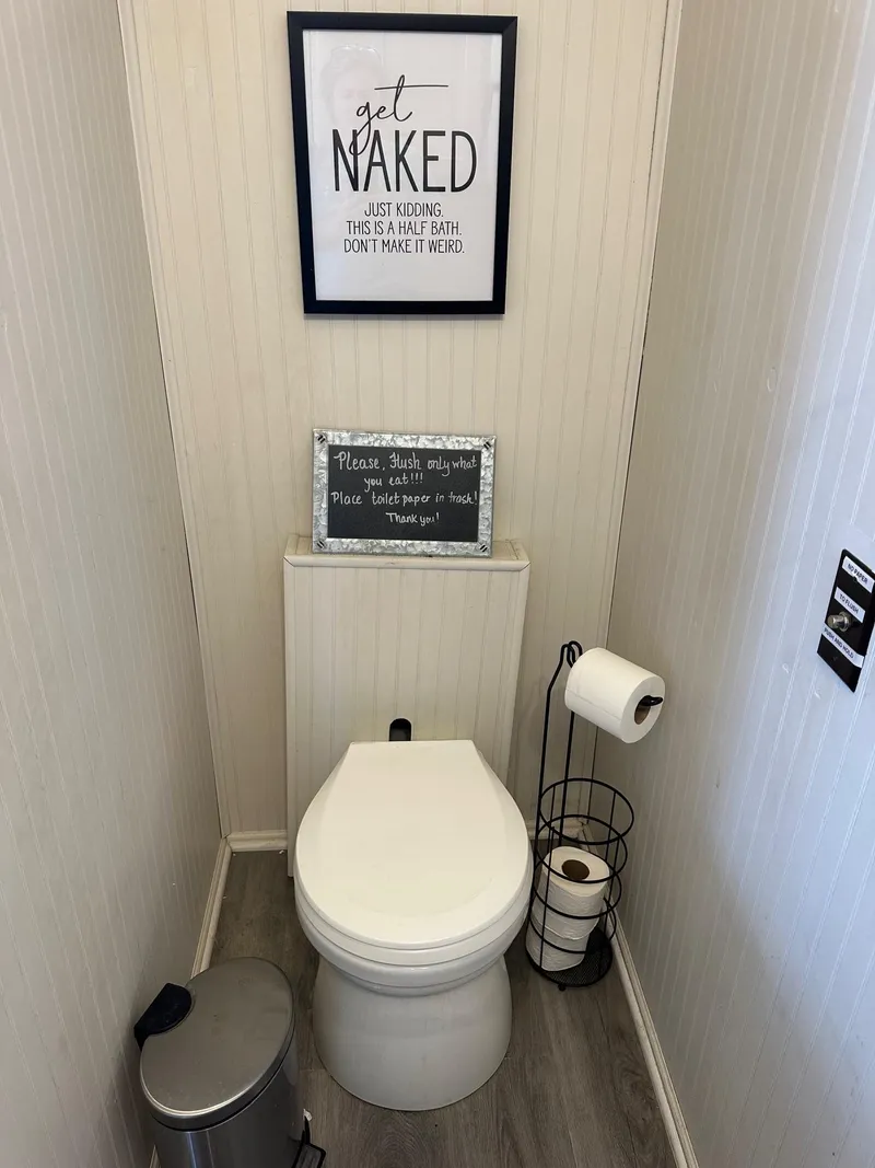Slide: The Image of Small bathroom with humorous wall art, toilet, and toilet paper holder. - 11