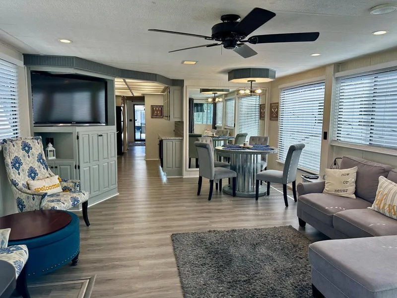 Slide: The Image of Spacious Lakeview 15x70 houseboat interior with modern decor, ceiling fan, and large windows. - 2