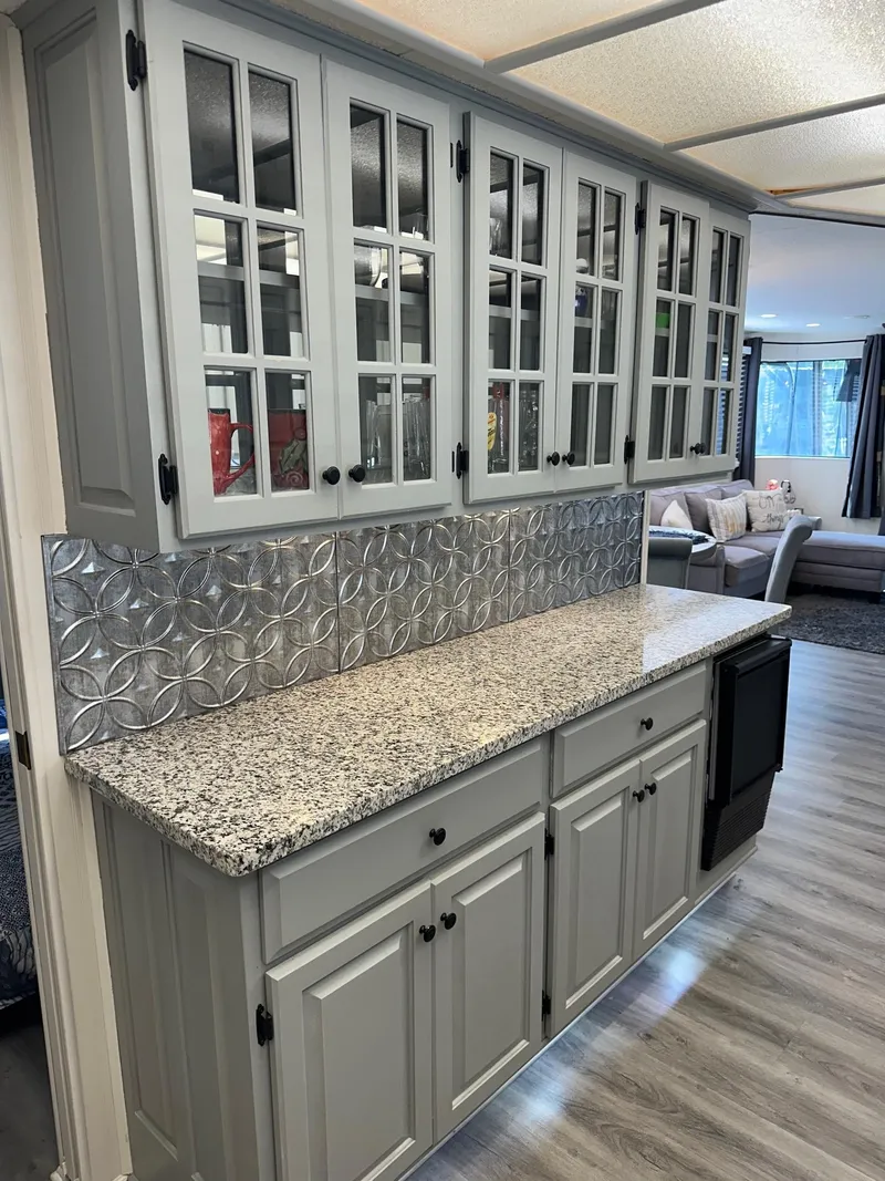 Slide: The Image of Gray kitchen cabinets with glass doors, granite countertop, and decorative backsplash in a Lakeview 15x70 model. - 5