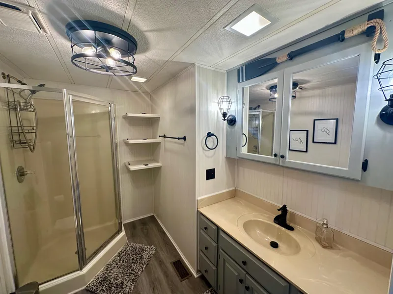 Slide: The Image of Modern bathroom with glass shower, beige countertop, and nautical-themed decor in a 1995 Lakeview model. - 8