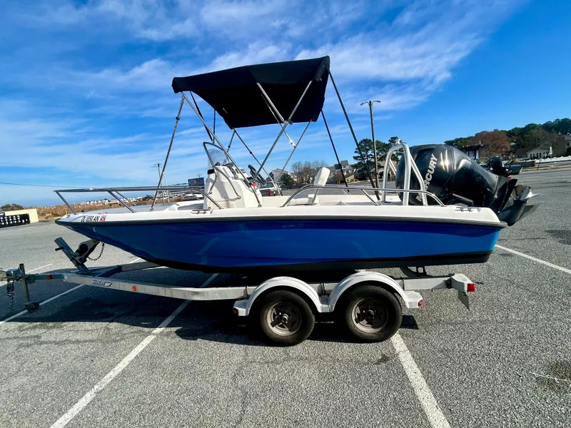 Slide: The Image of 2011 Boston Whaler DAUNTLESS 180/CC boat on trailer, blue hull, parked in lot. - 2