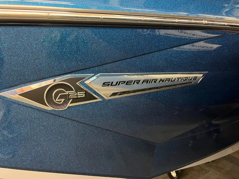 Slide: The Image of 2023 Nautique Super Air Nautique G25 boat emblem on blue metallic finish. - 14