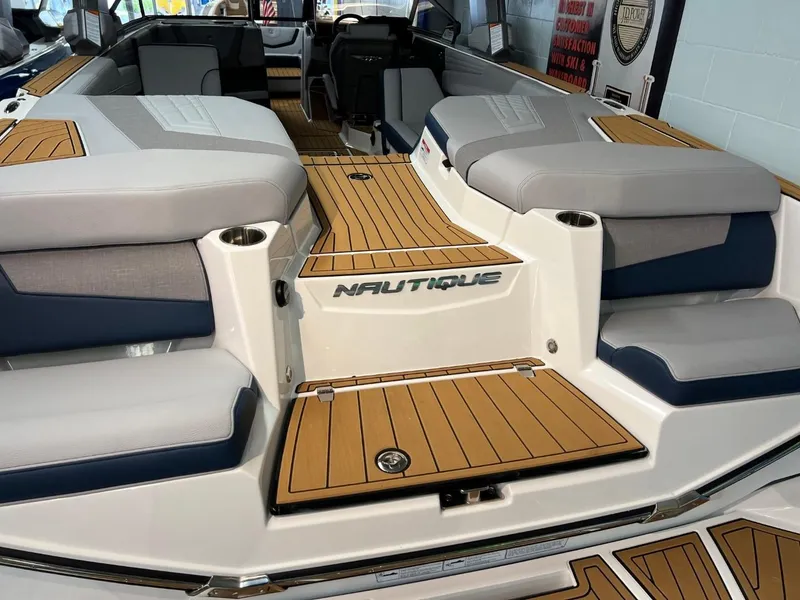Slide: The Image of 2023 Nautique Super Air Nautique G25 boat interior with teak flooring and cushioned seating. - 9
