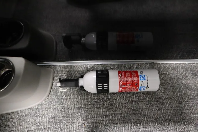 Slide: The Image of Fire extinguisher on carpeted floor of 2025 Trifecta 24RF LE 2.75 boat interior. - 31