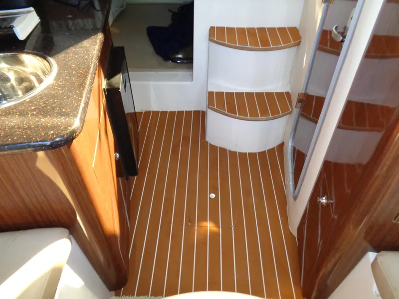 Slide: The Image of Interior of 2014 Regal 3060 Window Express boat with wood flooring and compact kitchen area. - 30