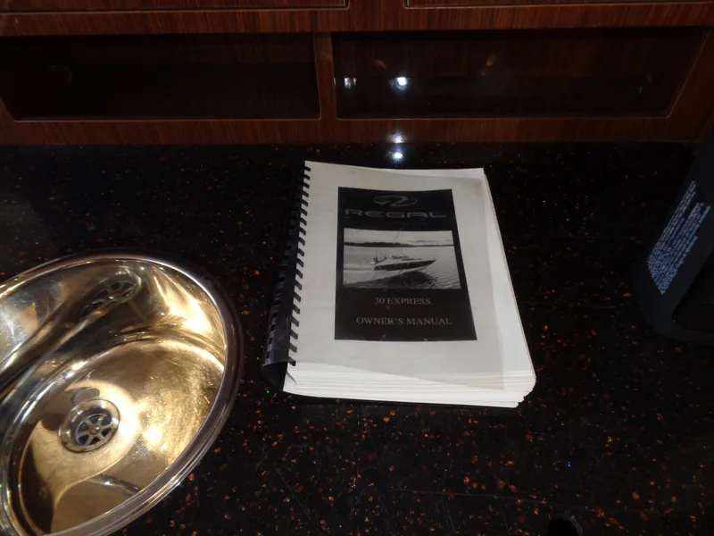 Slide: The Image of Regal 3060 Window Express 2014 owner's manual on dark countertop near sink. - 34