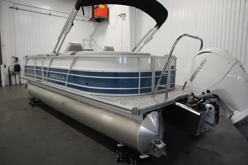 Slide: The Image of 2025 Trifecta 22RF LE 2.75 pontoon boat with Mercury outboard motor in a showroom. - 6