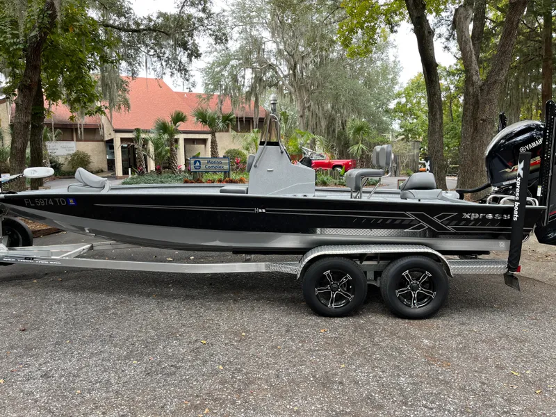 The Image of 2022 Xpress H22 boat on trailer, parked outdoors near trees and buildings. - 1