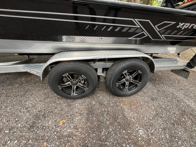 Slide: The Image of 2022 Xpress H22 boat trailer with dual black alloy wheels on asphalt. - 22