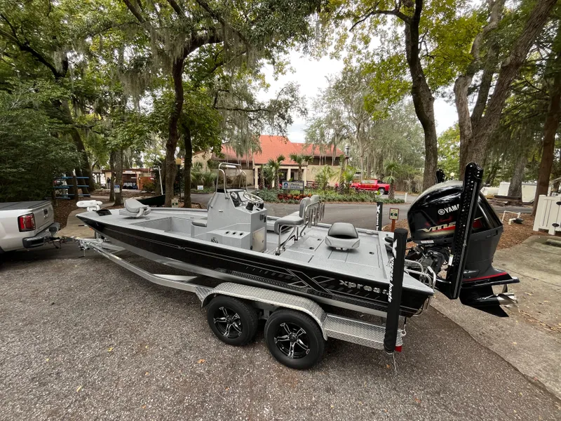 Slide: The Image of 2022 Xpress H22 boat on trailer, parked outdoors with trees in the background. - 3