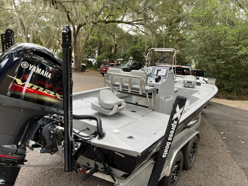 Slide: The Image of 2022 Xpress H22 boat with Yamaha engine, parked outdoors, surrounded by trees. - 6