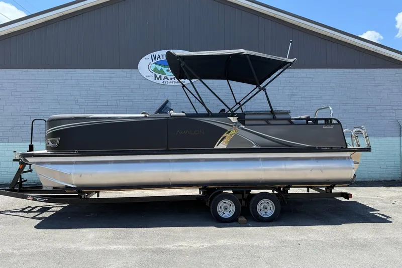 The Image of 2025 Avalon 2385 LSZ Elite Windshield pontoon boat on trailer, parked outside a building. - 4