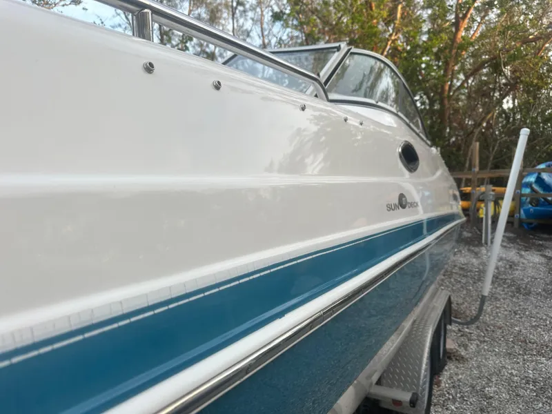 Slide: The Image of 2007 Hurricane SunDeck 237 OB boat, side view, parked on gravel with trees in background. - 5