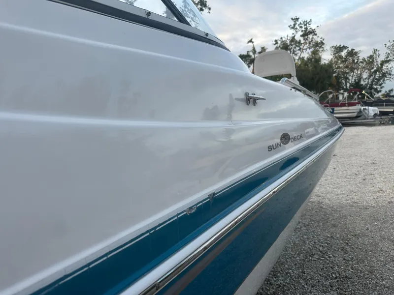 Slide: The Image of 2007 Hurricane SunDeck 237 OB boat, white and blue exterior, parked on gravel. - 7