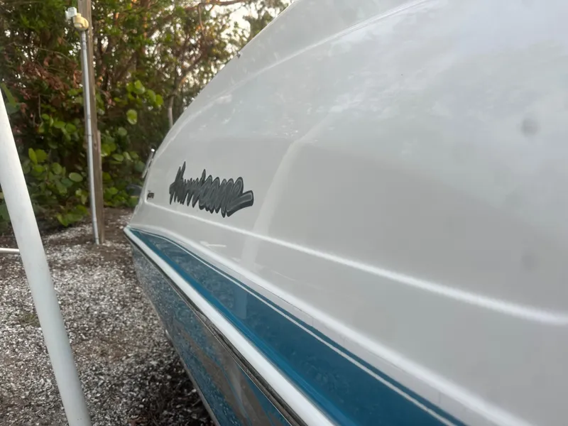 Slide: The Image of 2007 Hurricane SunDeck 237 OB boat, white and blue hull, parked on gravel. - 8
