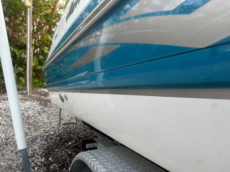 Slide: The Image of 2007 Hurricane SunDeck 237 OB boat side view with blue and white detailing. - 9