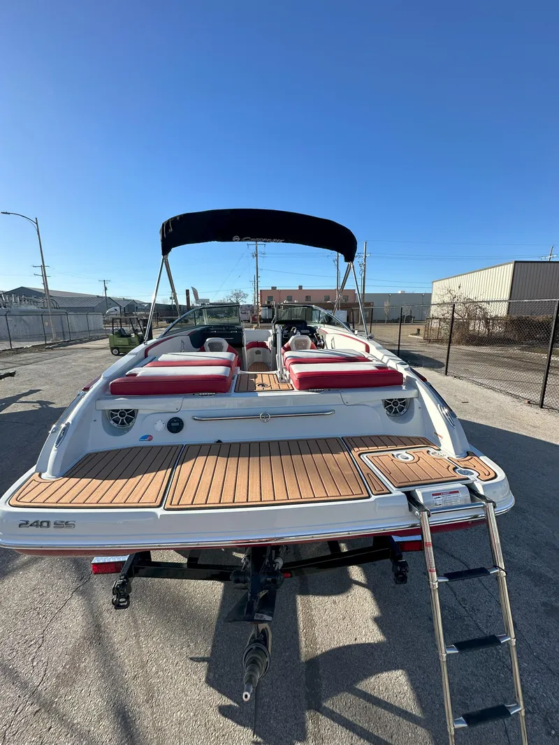 Slide: The Image of 2025 Crownline 240 SS boat with red seating and swim platform in a sunny marina. - 10