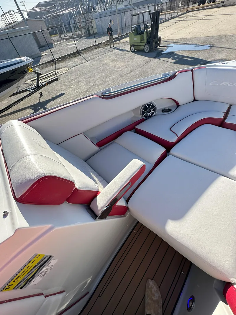 Slide: The Image of 2025 Crownline 240 SS boat interior with red and white seating, docked outdoors. - 12