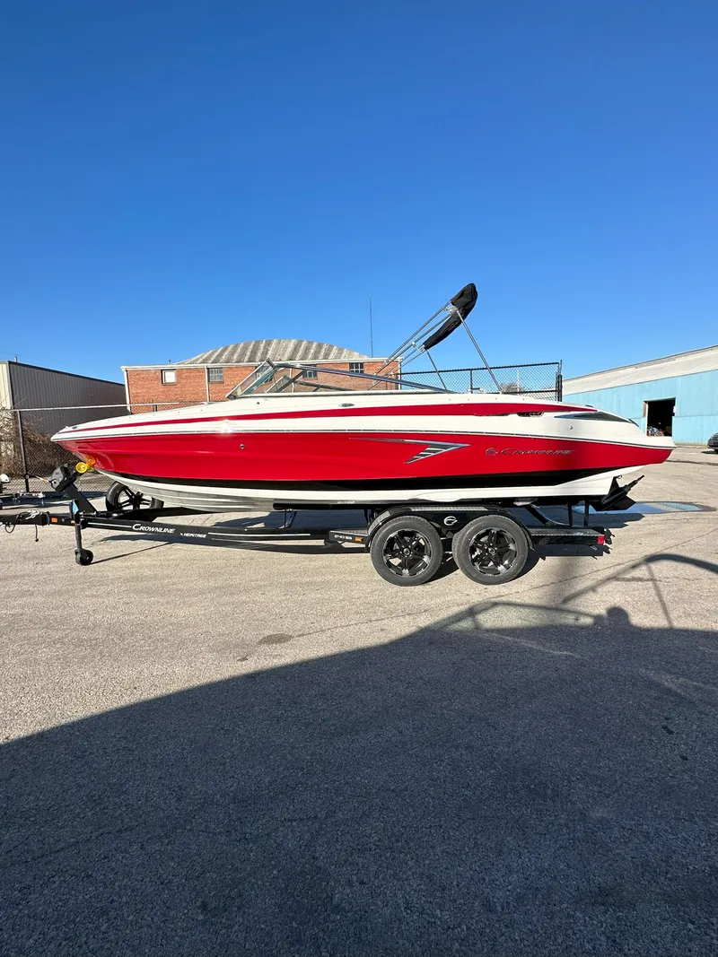 Slide: The Image of 2025 Crownline 240 SS boat in red on a trailer, parked outdoors. - 4
