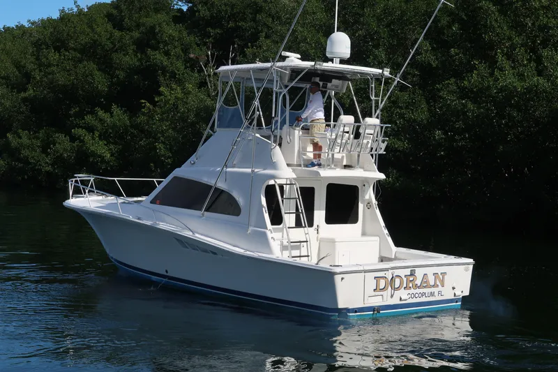 Slide: The Image of 2002 Luhrs 40 Convertible boat on calm water near lush greenery. - 4